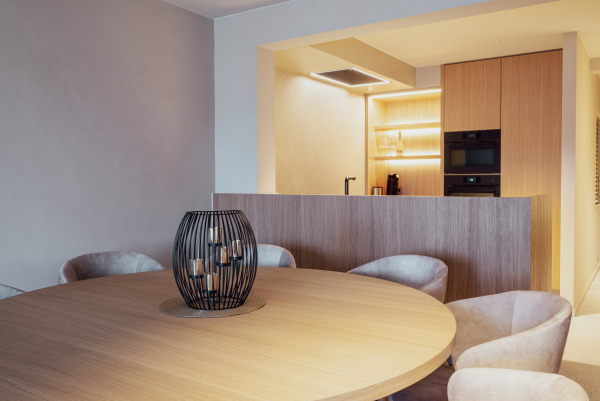 Keuken in warme houttinten met open rek en zwarte inbouwtoestellen, perfect geïntegreerd in een gezellig interieur.